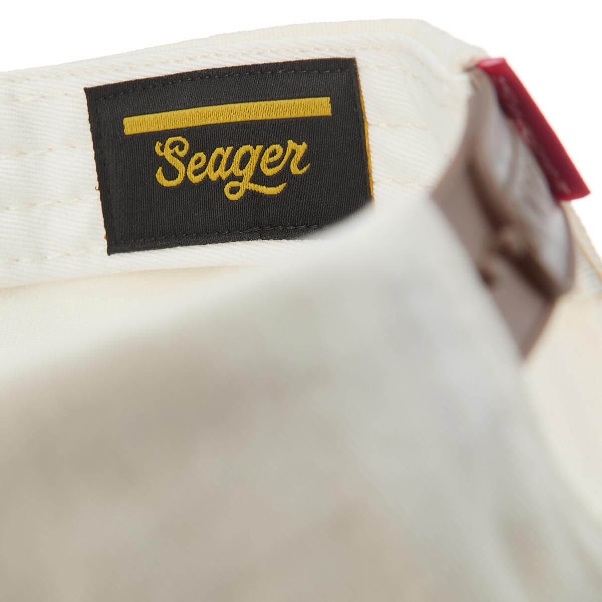 Close-up of a white baseball cap with a black 'Seager' logo tag.